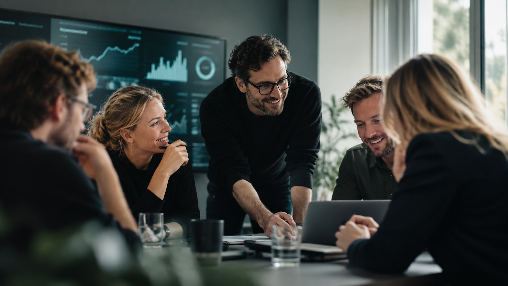 The Mimero team collaborating around a conference table with a dashboard of business data on the wall behind them